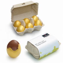 Sechser-Eierkartons mit goldenen Eiern und Loomis-Osterbanderole sowie geöffnetem Schokoladenei