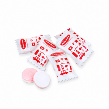 Einzeln verpackter Traubenzucker mit rotem Firmenaufdruck auf weisser Folie und zweifarbigen runden Tabletten mit zwei Aromen
